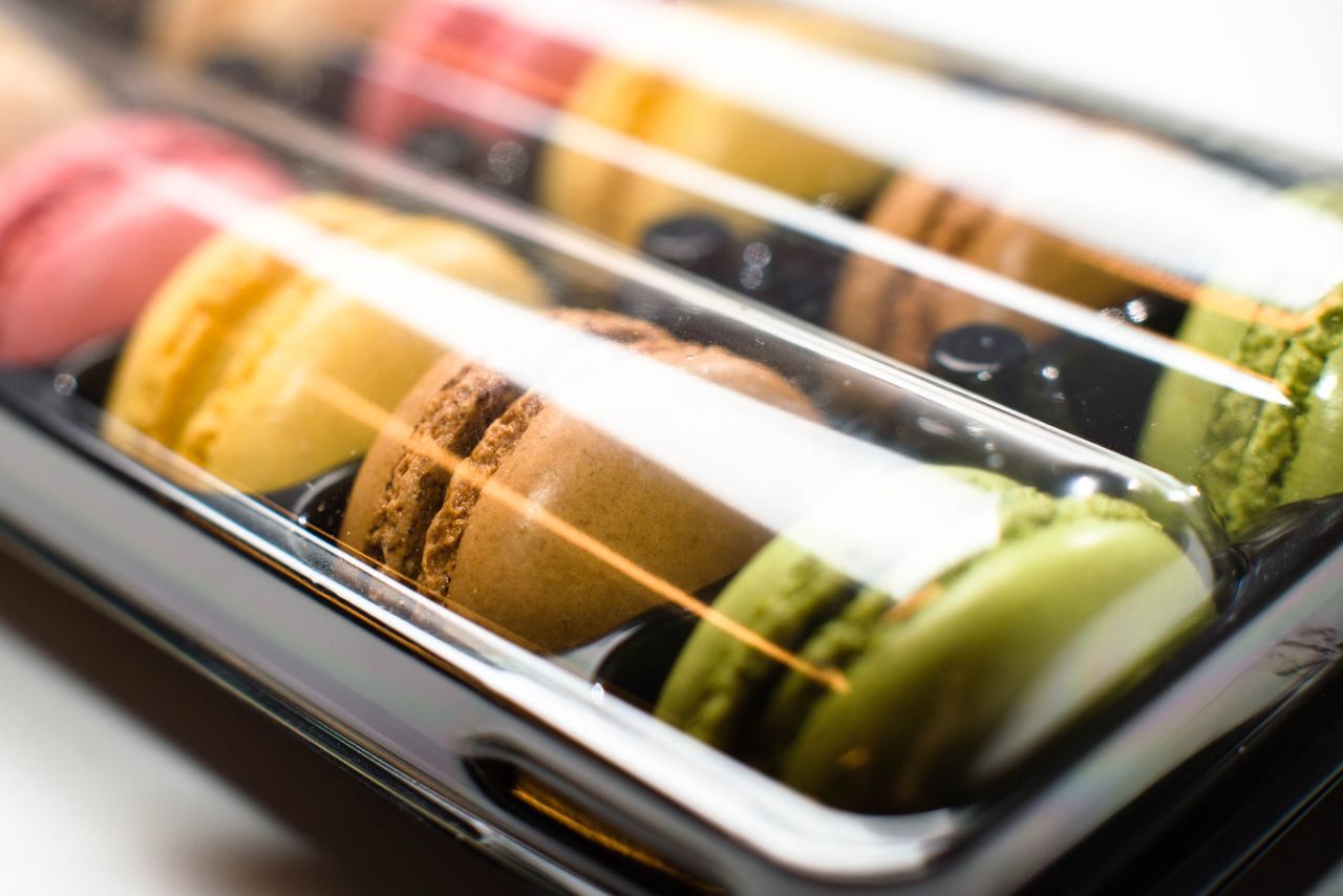 Close-up of colorful French macarons in a plastic box, ready to enjoy.