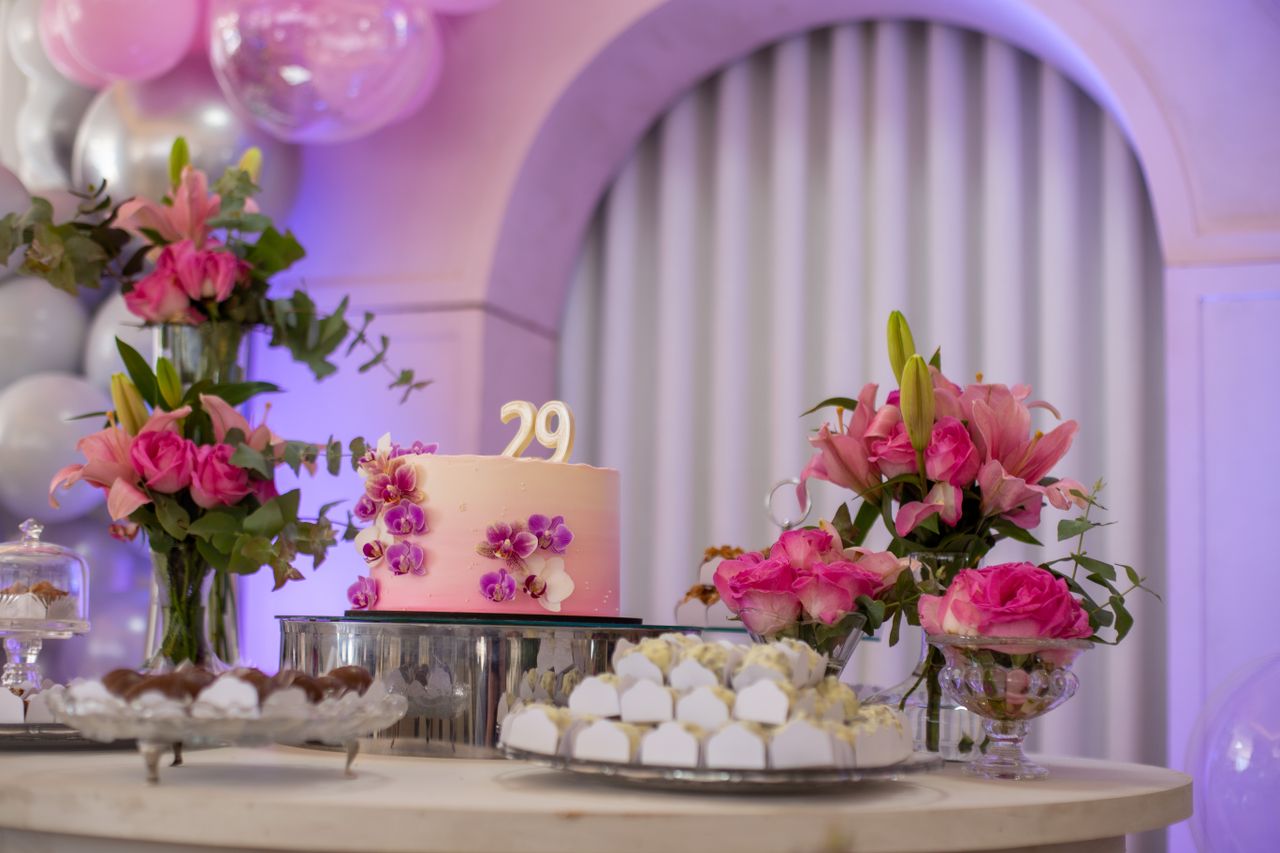 A beautifully decorated birthday cake with flowers and sweets on a table indoors, perfect for celebrations.